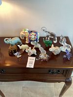 Full view of all 15 elephant figurines arranged on a wooden table showing variety of materials and sizes.