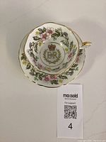 Top view showing teacup placed on saucer, floral design with gold trim and central crown and E II R emblem