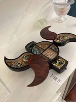 Open wooden crescent jewelry box showing multiple compartments filled with various jewelry pieces