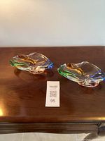 Pair of Mid-Century Modern art glass bowls with multicolor accents placed on wooden surface.