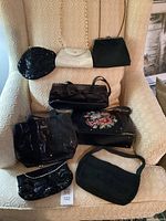 Overview of all 8 vintage purses displayed on chair, showing variety of materials including beaded, leather, needlepoint, and fabric.