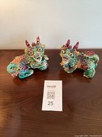 Front and side view of both ceramic Foo Dogs placed on a wooden surface showing vibrant colors and detailed craftsmanship.