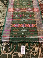 Full length view of one embroidered Batak shoulder cloth showing overall pattern, colors, and fringe ends.