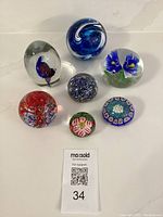 Full display of the 7 vintage glass paperweights showing variety in size, shape and colors.