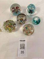 Overview photo showing all 6 vintage glass paperweights with varied internal designs and colors.