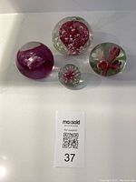 Top-down view of all four vintage glass paperweights showing floral patterns inside clear glass.
