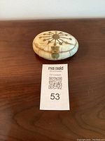 Top view of oval trinket box displaying brass sunburst inlay pattern and delicate latch.