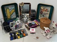 Wide view of assorted household items including vintage seed trays, stoneware jar, plush toys, and small office supplies.