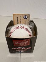 Photo showing official Rawlings Major League Baseball inside its box with certificate of authenticity behind it, plastic wrapping visible