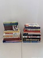 Photo of two stacks of business and financial books including titles on real estate, investing, analysis, and personal success.