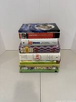 Front view of stack of seven assorted cookbooks, mostly focused on vegetarian cooking and joy of cooking series.