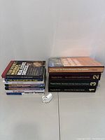 Two stacks of books with titles focused on finance and real estate, and a pair of white wireless earbuds with charging case placed in front.