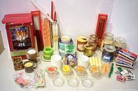Photo of assortment of candles, candle holders, and matches including boxed taper candles, glass jar candles, votives, tealights, matchboxes, and matchbooks.