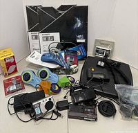 Full view of lot showing label makers, cassette recorders, scale, camera, tapes, and accessories arranged on table