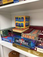 Photo of assorted games on shelf including Mad Gab, Racko, Vintage Outburst, Cranium and Scrabble Deluxe