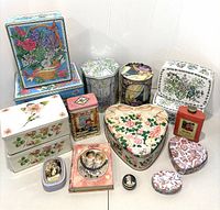 Photo showing the full assortment of 17 tins in various shapes and designs laid out on a flat surface.