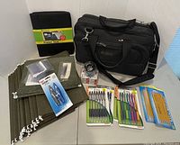 Groupshot of all items including black computer bag, binder/planner cover, pens, pencils, stapler, and folders on table