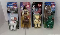 Four Ty Beanie Baby bears in original packaging displayed in a row: Maple, Britannia, Glory, Erin.