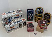 Wide shot showing the assortment of white '88 Baseball team logo sticker & trading card tin boxes, vintage round baseball player tins featuring players like Willie Mays and Carlton Fisk, and Michael Jordan rectangular collector card tins, including unopened and loose tins.