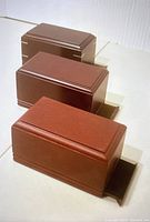 Three wooden rectangular boxes stacked, showing reddish-brown wood with groove molding on lids
