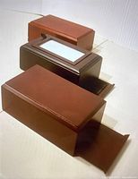 Three wooden boxes in different brown shades, one with a glass window lid, photographed on a white surface.