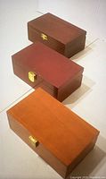 Three rectangular wooden boxes in different shades of brown, each with a hinged lid and metal clasp on front.