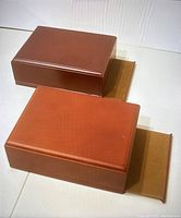 Two wooden boxes shown from top to side angle with brown finish.