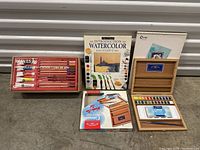 Front view of all art supplies and watercolor kit set including paints, books, palettes.