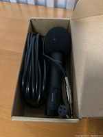 Microphone and attached cable inside a cardboard box on a wooden surface