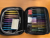 Knitting needle set with interchangeable tips and accessories organized in a zippered black case
