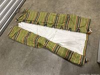 Hammock folded inside matching striped fabric carrying bag, showing fabric pattern and bag drawstring