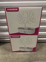 Two boxed Penobon light up trees in original packaging stacked vertically.