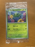 Front view of sealed Oddish Pokémon card showing artwork and attack details.