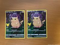 Two identical Pikachu Celebrations Pokémon cards on a wooden surface.