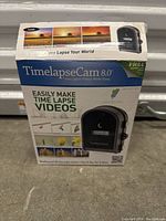 Front view of TimelapseCam 8.0 box showing the product image, usage examples, and branding.