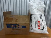 Box labeled Uline and large plastic bag of boot covers