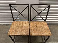 Front view of two wicker seat chairs with metal frames showing the woven seat details and X backrest design.
