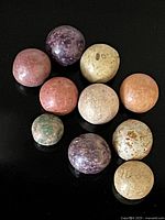 Set of 10 handmade Civil War era clay marbles in assorted colors laid out on black surface. Shows general size, texture, and color variety.