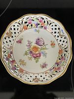 Top view of porcelain bowl showing intricate lattice edge and colorful floral hand-painting with gold accents