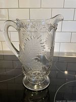 Full view of the clear pressed glass water pitcher with maple leaf etching and scalloped rim.