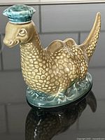 Front view of the ceramic Loch Ness Monster decanter with green hat lid, showing textures and painted details.