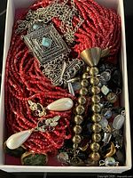 Jewelry pieces showing multi-strand red bead necklace, silver clasp with turquoise stones, freshwater pearl earrings, and other beads