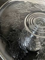 Close-up photo of the pressed glass pedestal's maple leaf pattern and central platform, showing detail and bubbles in the glass.