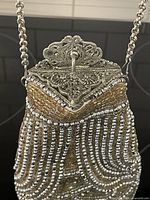 Close-up of the silver filigree diamond-shaped clasp and chain handle with champagne and silver bead detailing on the upper section of the bag.