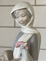 Close-up view of the girl's face and the cockerel she is holding, showing hand-painted details and soft color palette with white headscarf