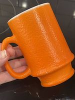 Full view of textured orange peel surface on milk glass mug with D handle.
