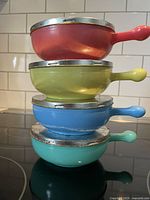 Stacked bowls with metal lids visible, showing wear and reflective chrome finish with scratches.