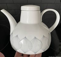 Side view of white ceramic teapot with grey geometric design on the lower body.