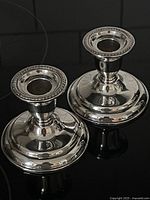 Pair of silverplate Birks Regency candlesticks showing full body and polished shine on black reflective surface.