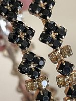 Close-up image showing the intricately claw-set black and champagne gold rhinestones on one bangle, highlighting the detailed setting and craftsmanship.